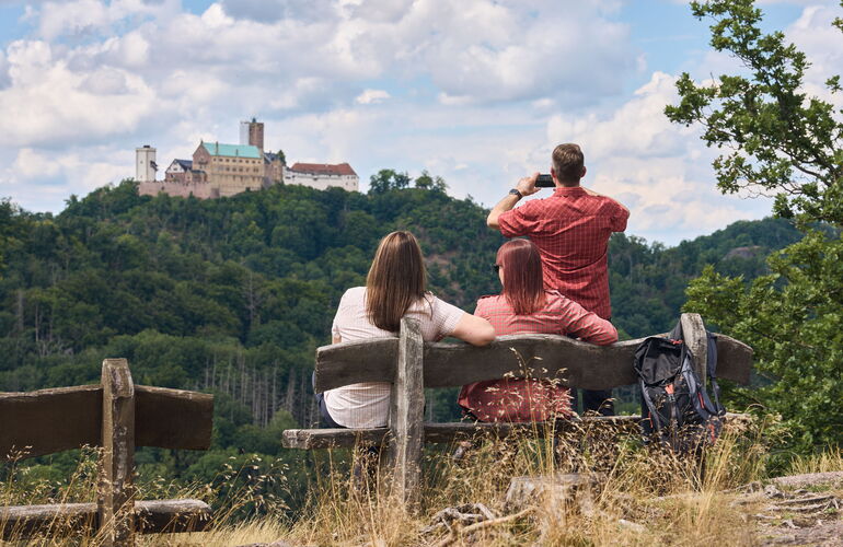 Drei Wanderer genießen den Ausblick vom Breitengescheid bei Eisenach zur Wartburg