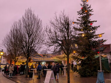erleuchteter Kirchplatz mit Ständen und Menschen
